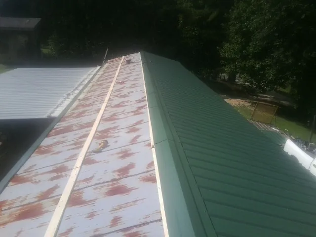 Old rusted panels beside newly installed green metal roofing — Wind Damage Roof Repair by Roofing Brothers in Schererville