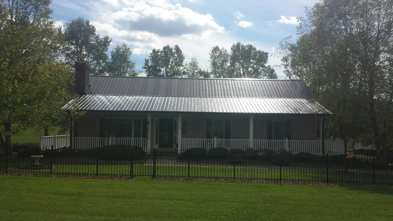 Gray metal roof on a brick ranch with a full width front porch — Gutter Guard Installation work by our crew in Schererville