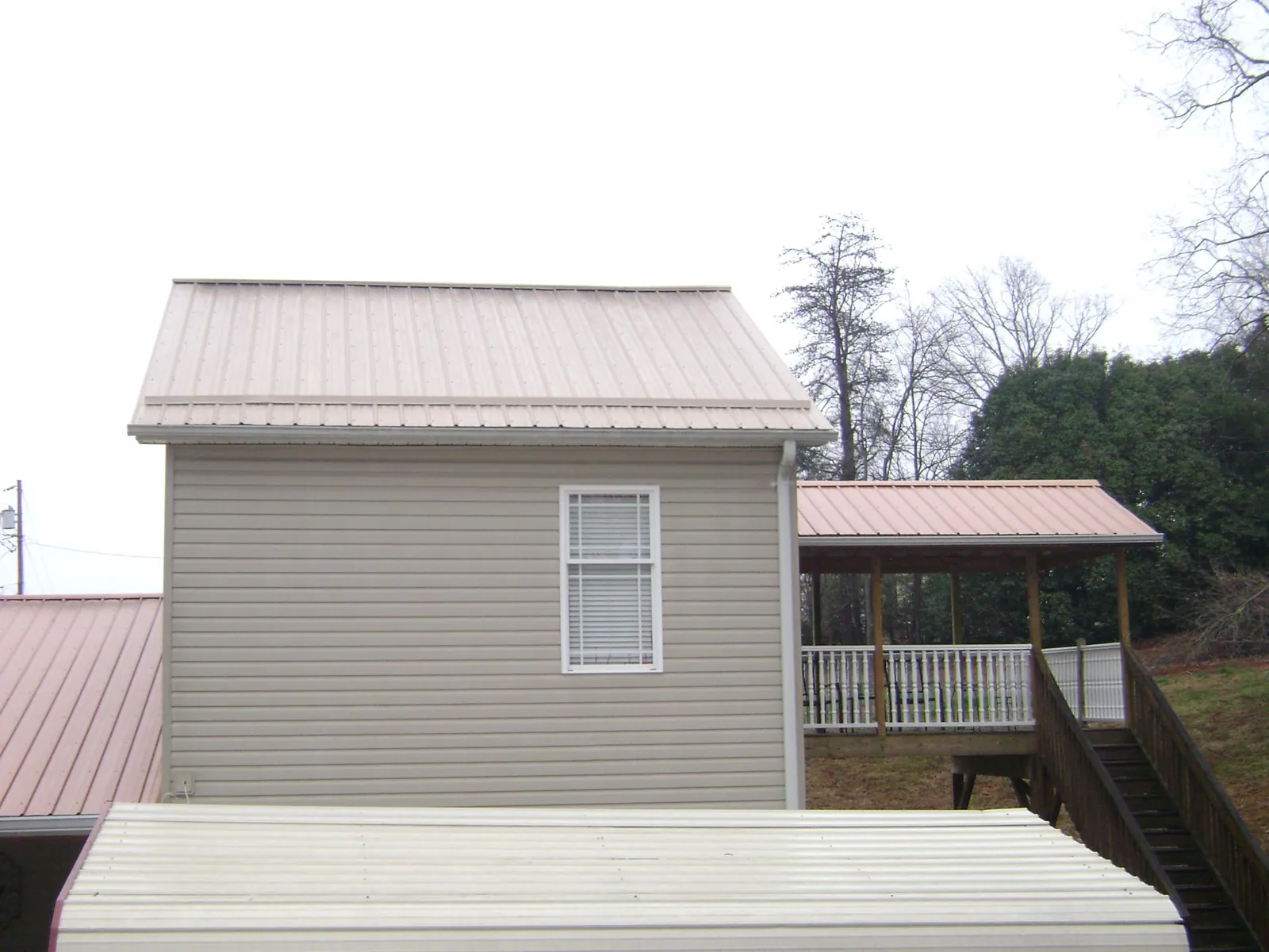 Tan metal roofs on a two story addition and attached porch, from a Roof Replacement job in Schererville