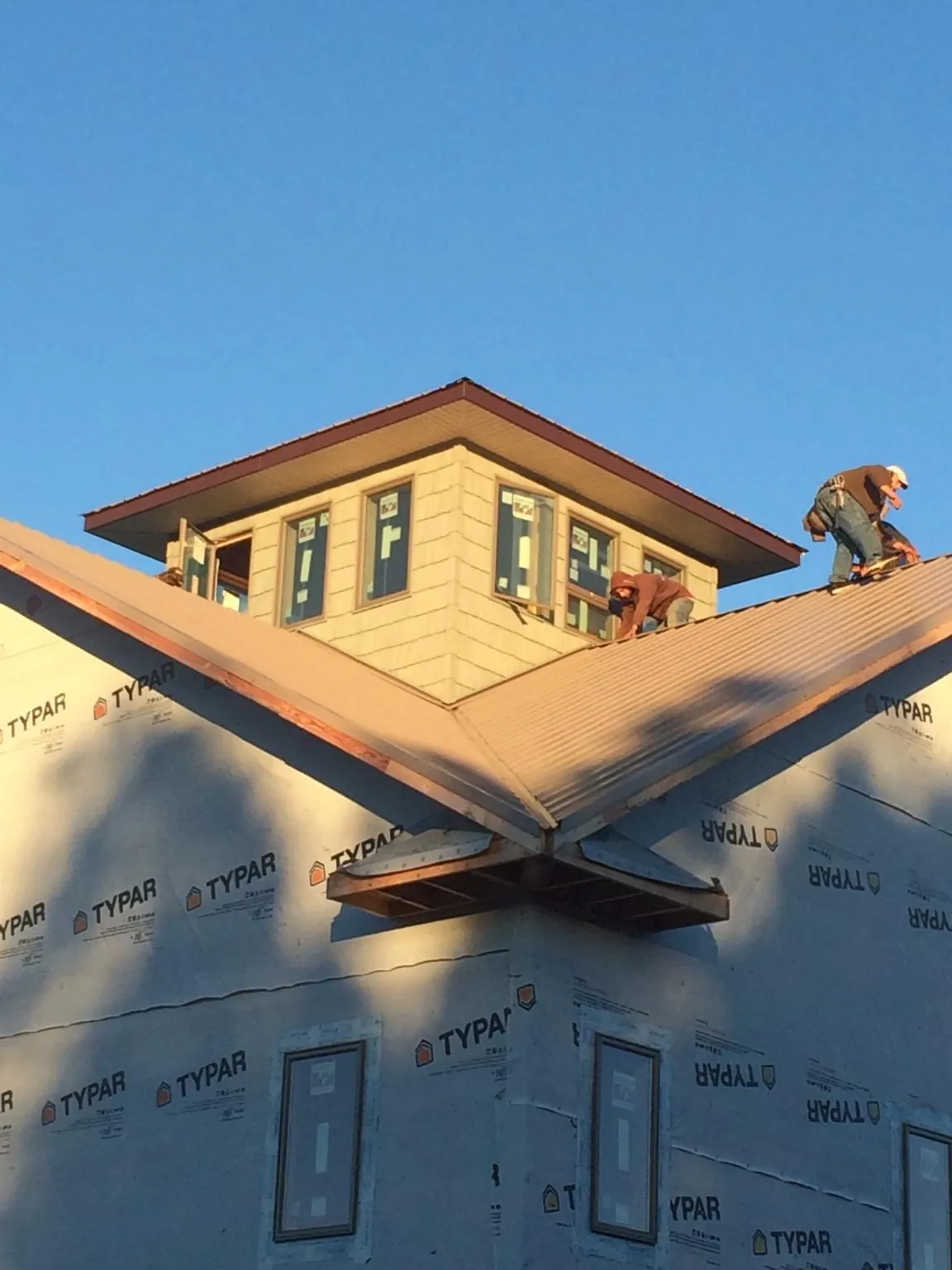 Roofers working around a rooftop cupola on a new metal roof at sunset — Roof Waterproofing in Schererville by Roofing Brothers